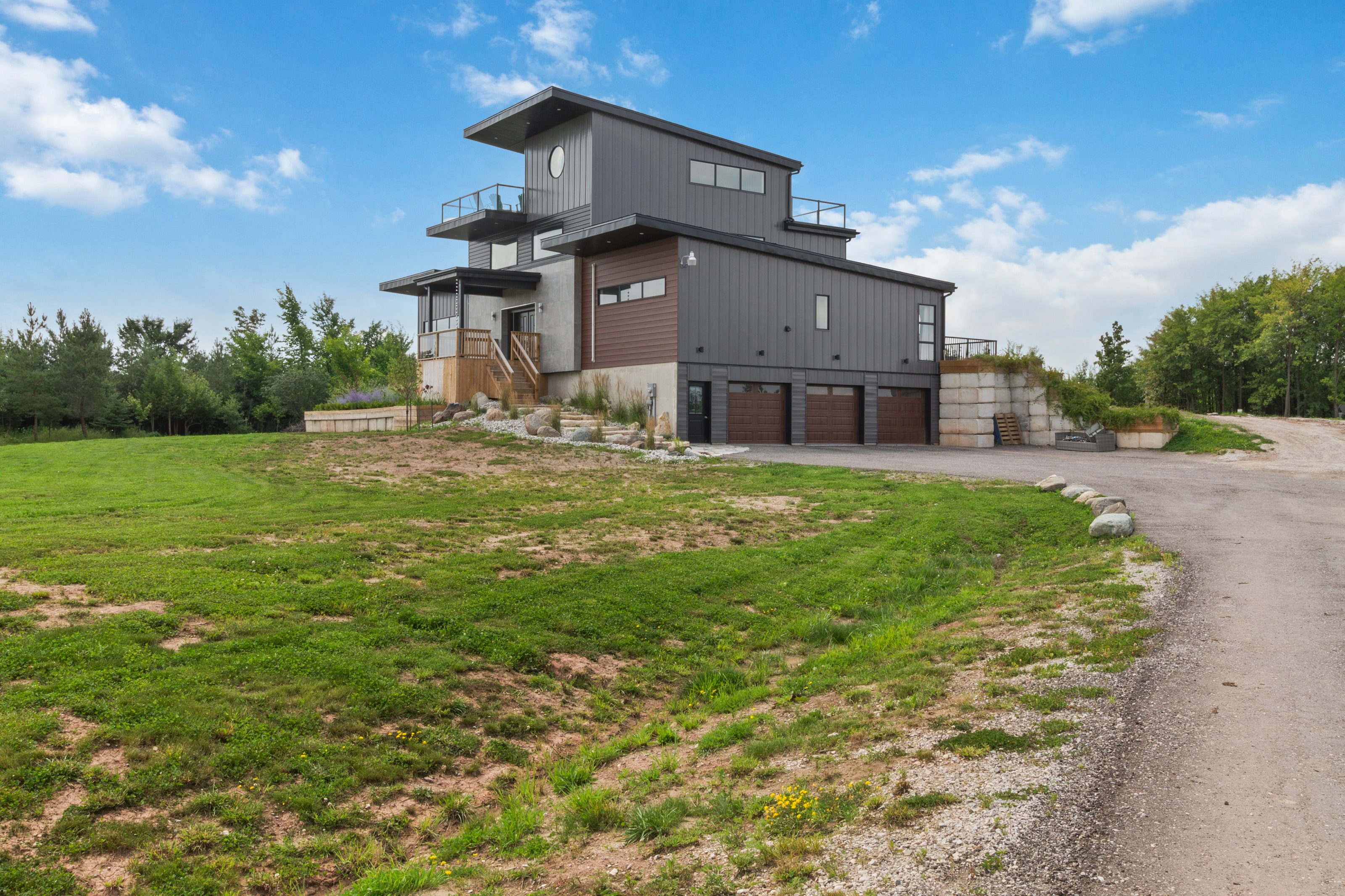 The house seen across a sloping meadow, with the garage and drive at the lower level