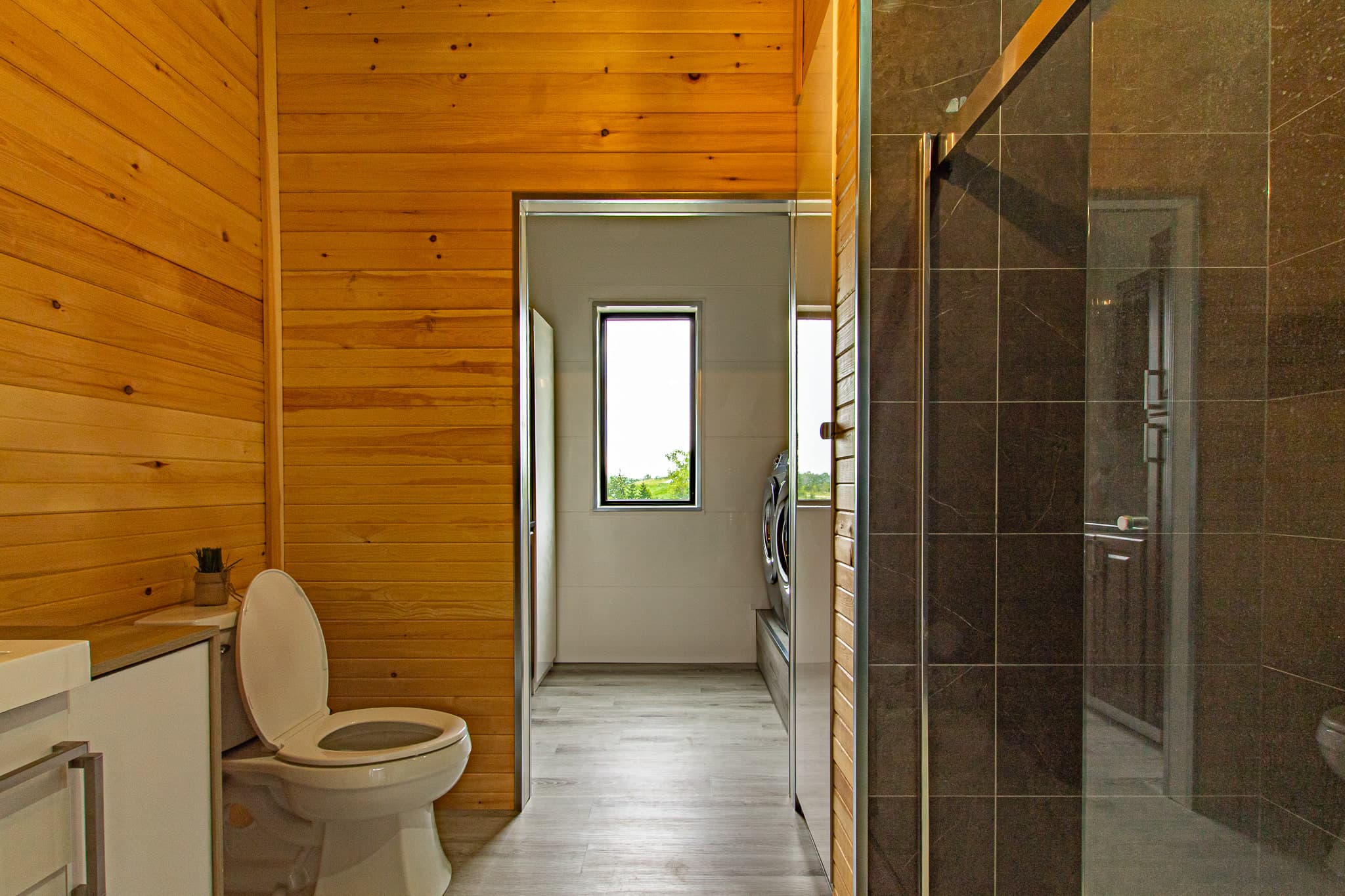 A pine-lined bathroom with a doorway through to a laundry area with washer and dryer
