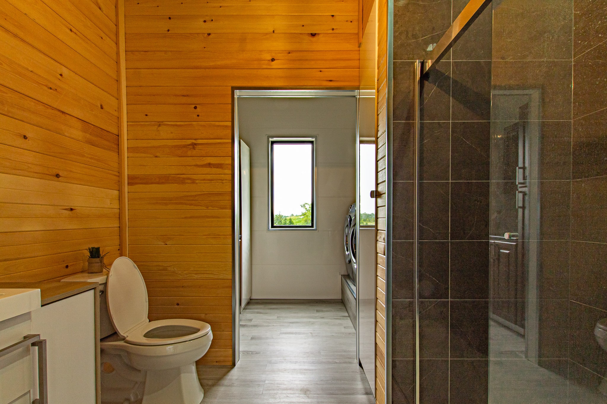 A pine-lined bathroom with a doorway through to a laundry area with washer and dryer