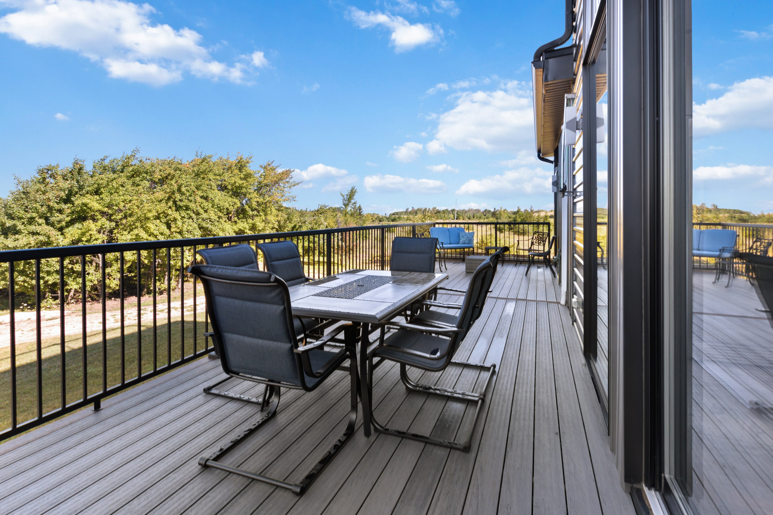 The outdoor dining table on the deck under a wide sky of scattered cloud