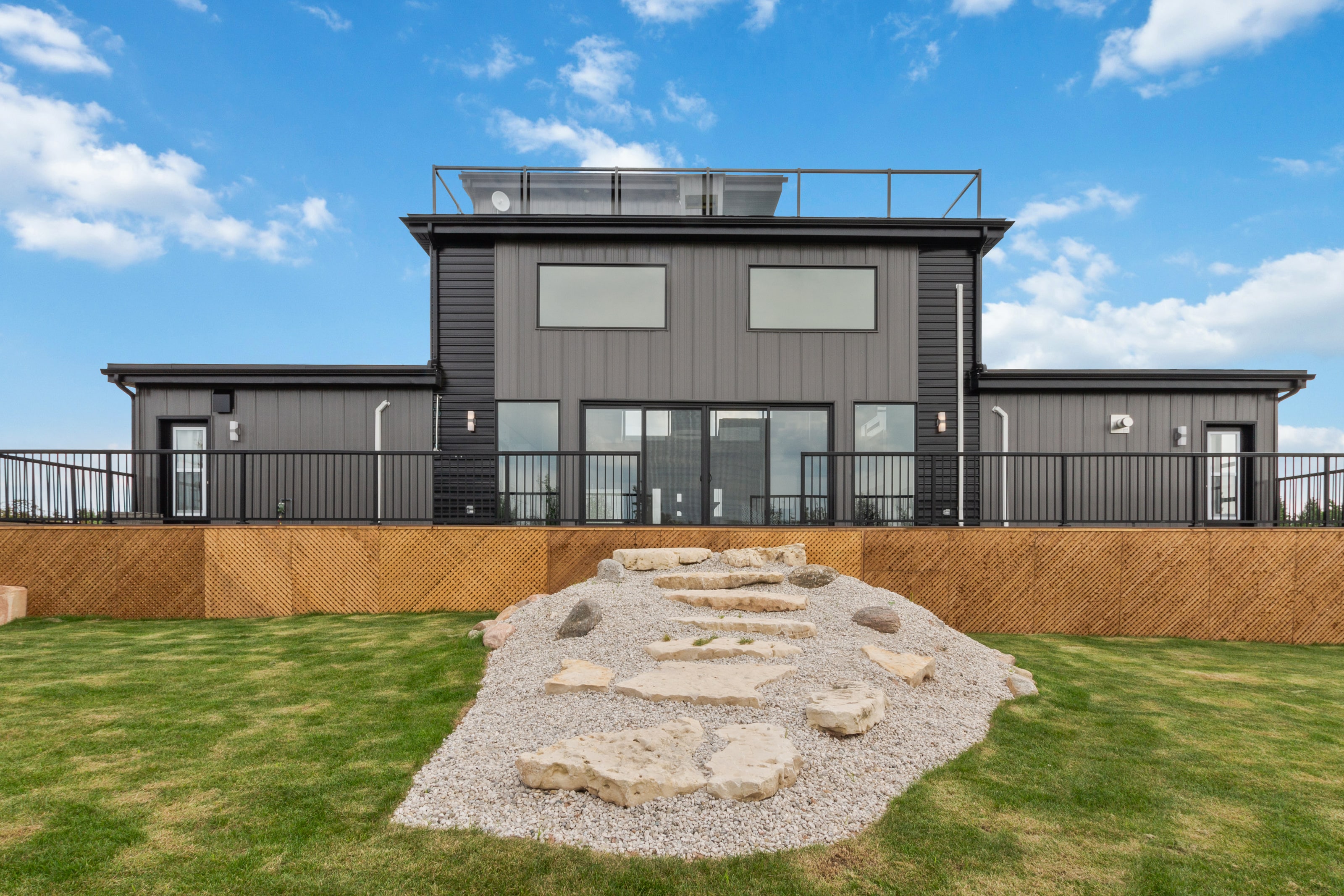 The rear elevation in late light, with the rooftop terrace railing visible along the roofline