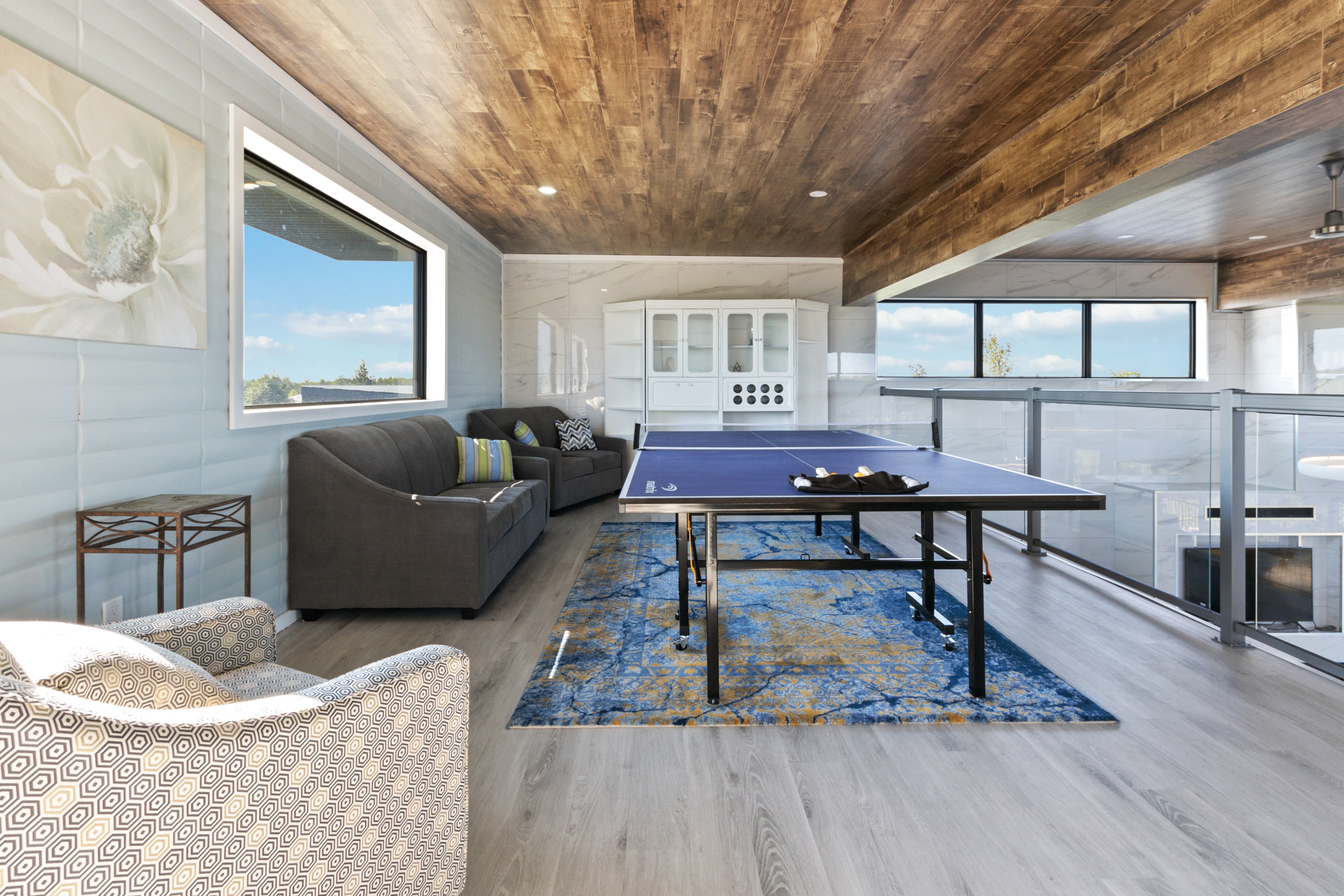 A table tennis table in the upper loft with sofas either side under a plank timber ceiling