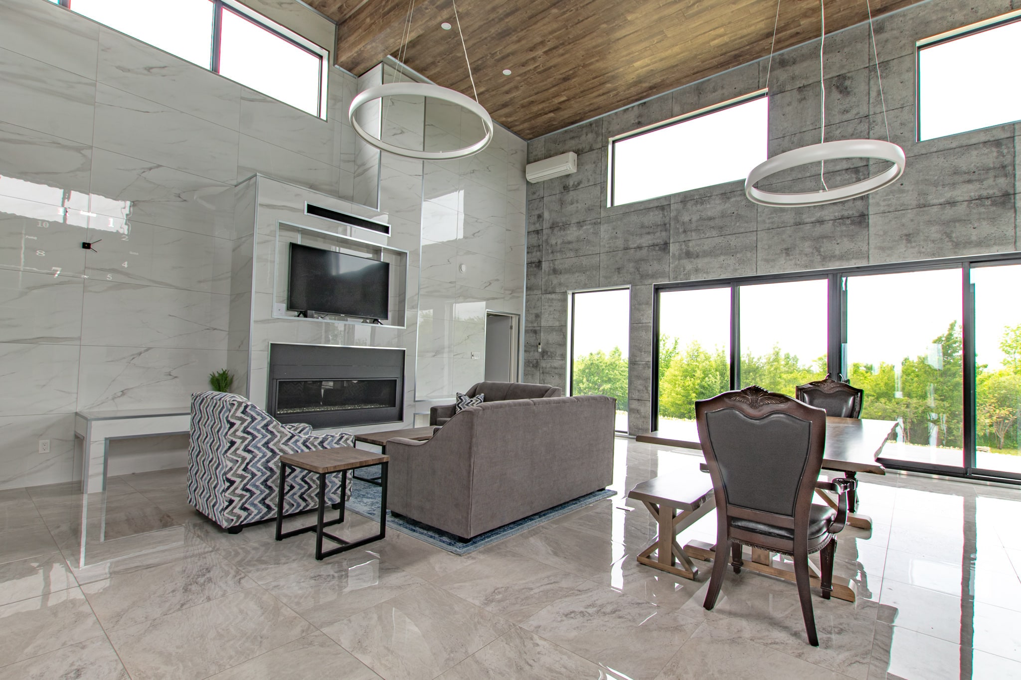 The living and dining area together, with the concrete wall on one side and full-height glazing on the other