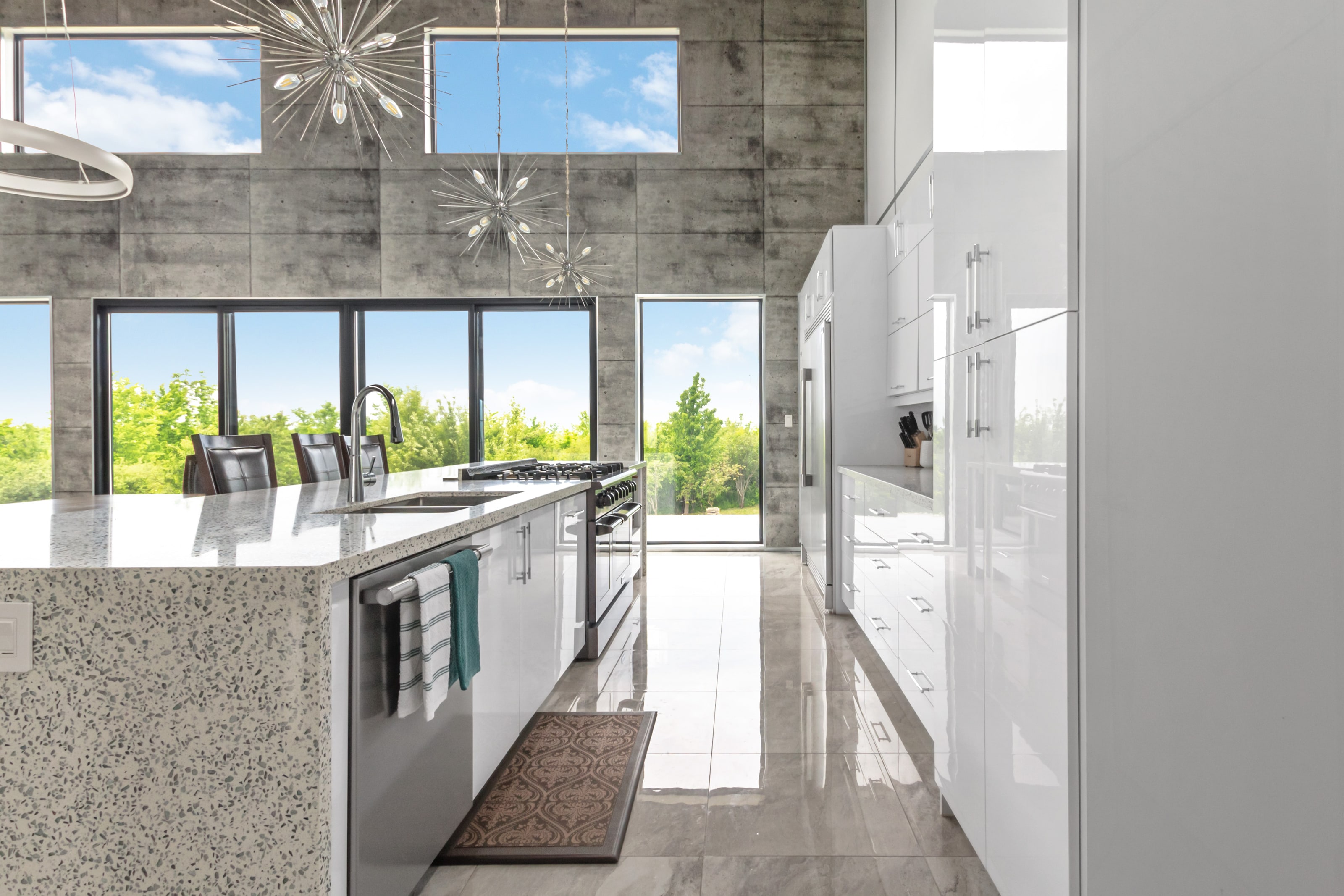 A long granite-topped kitchen island in front of a wall of glass doors opening to the deck