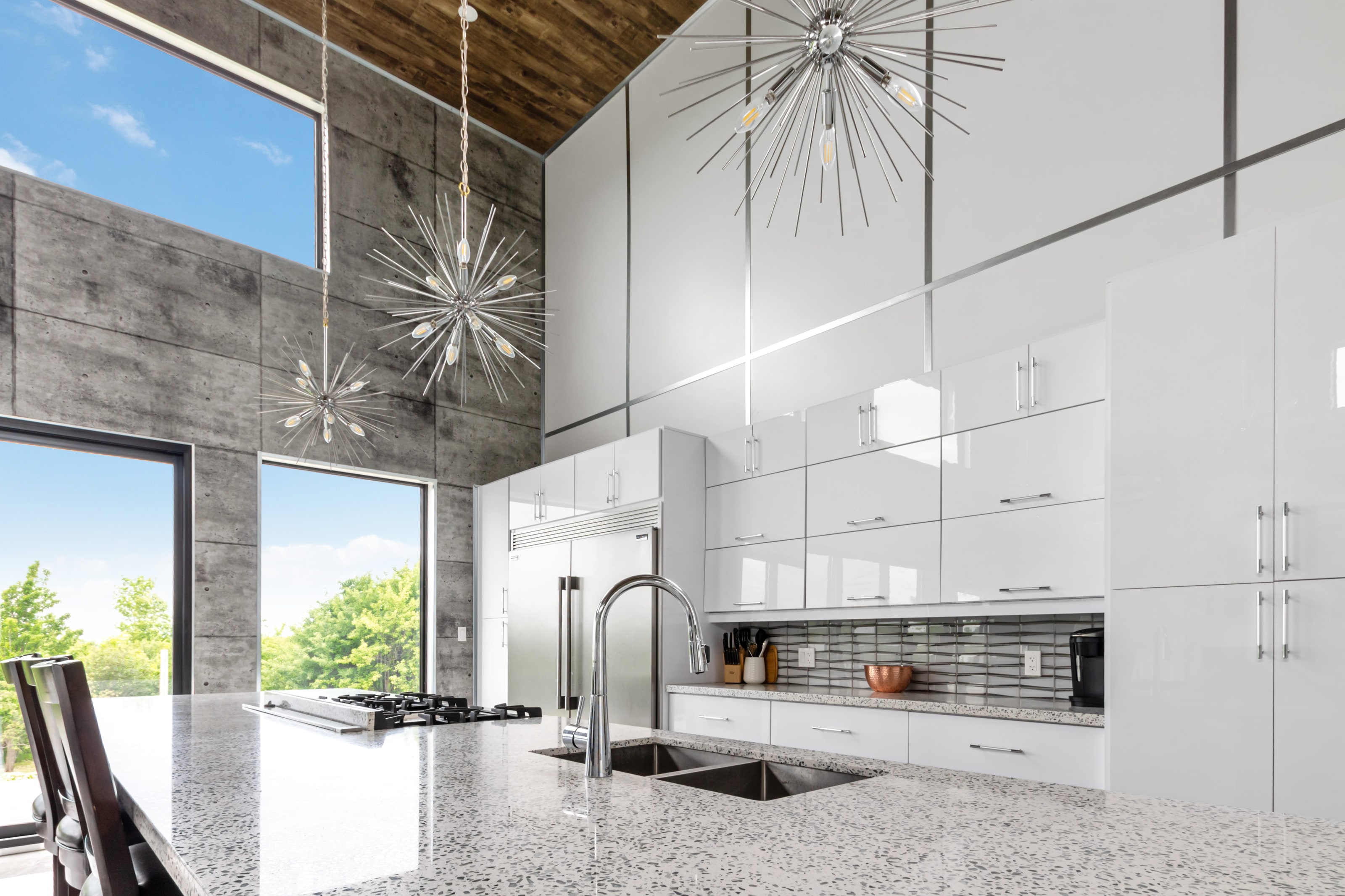 The kitchen run with gloss white cabinetry, gas cooktop, deep sink and sputnik pendants overhead