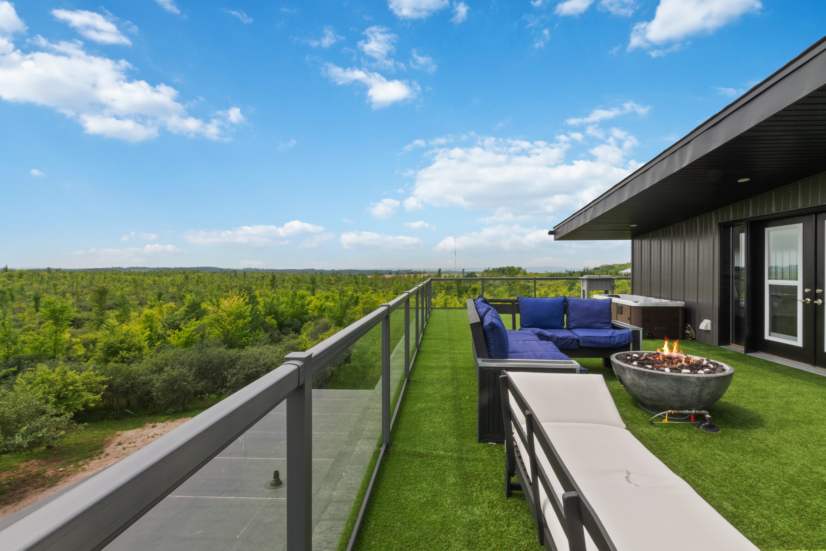 The fire bowl lit on the rooftop terrace with the hot tub and pavilion behind