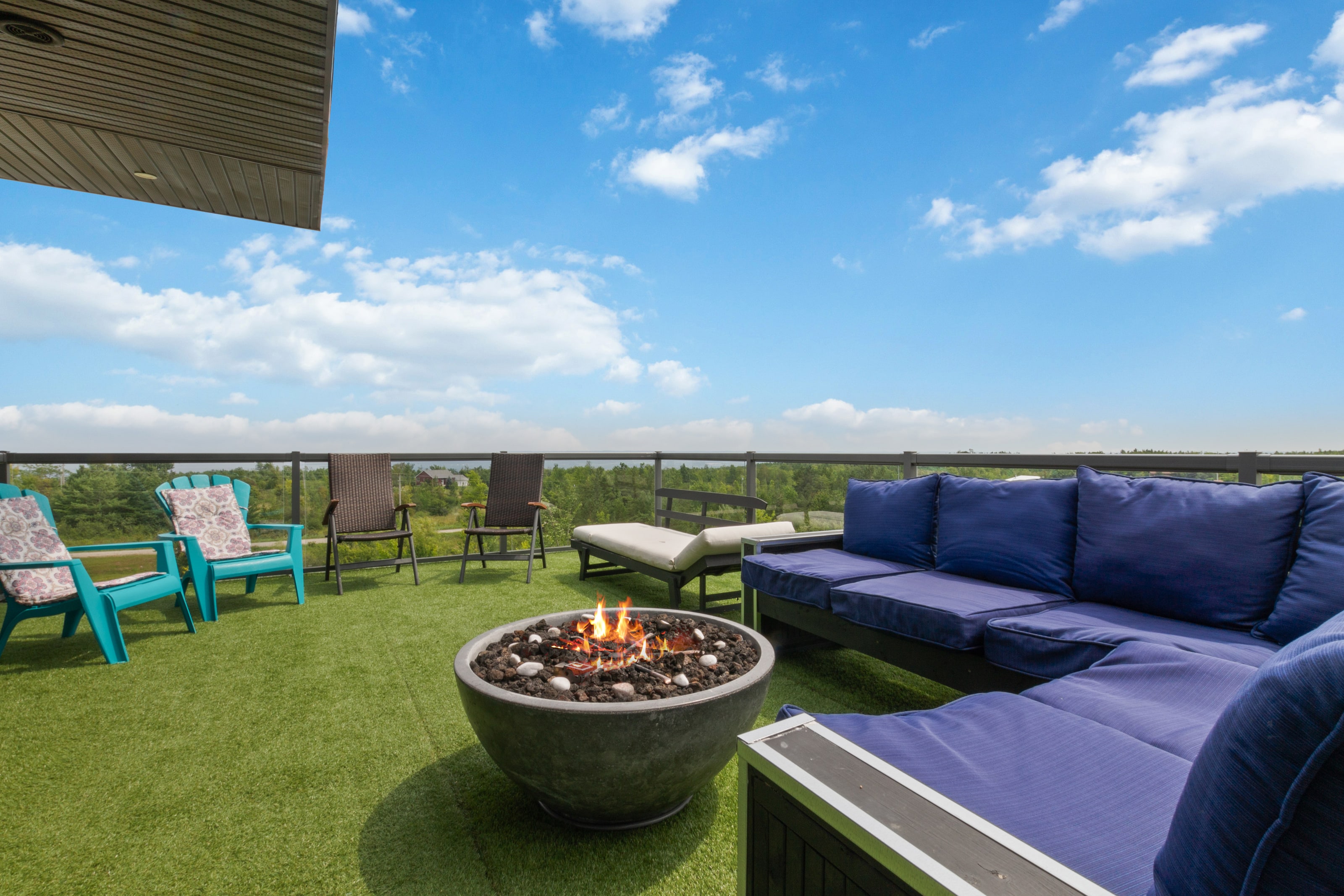 Rooftop seating around a lit fire bowl, with loungers and chairs facing the view over the treetops