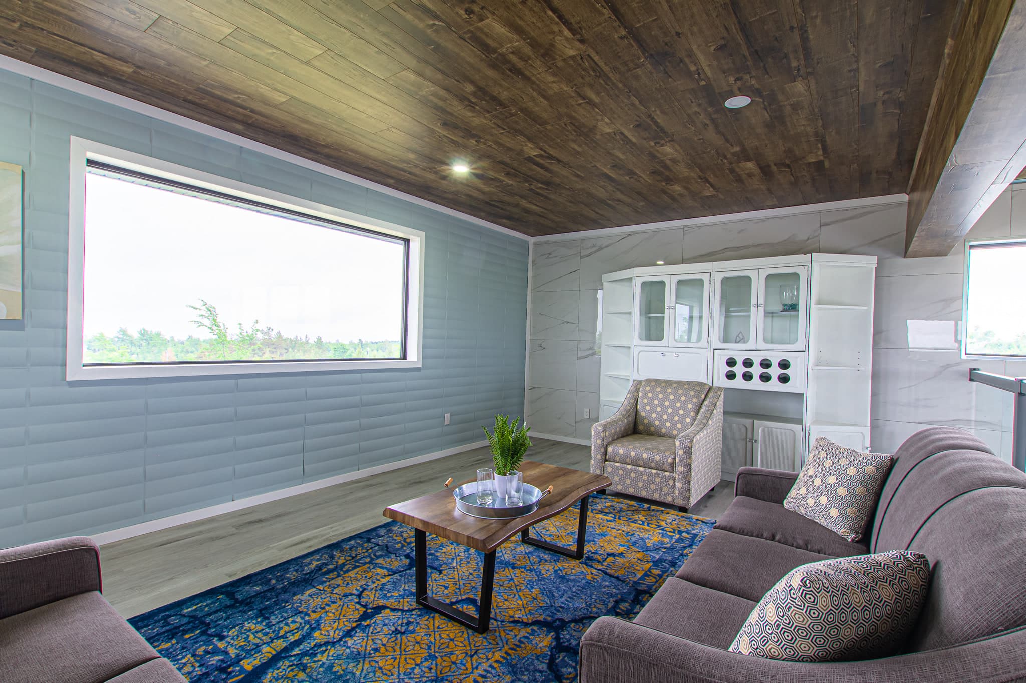 A quiet upstairs sitting room with sofas, a glazed hutch and a long ribbon window