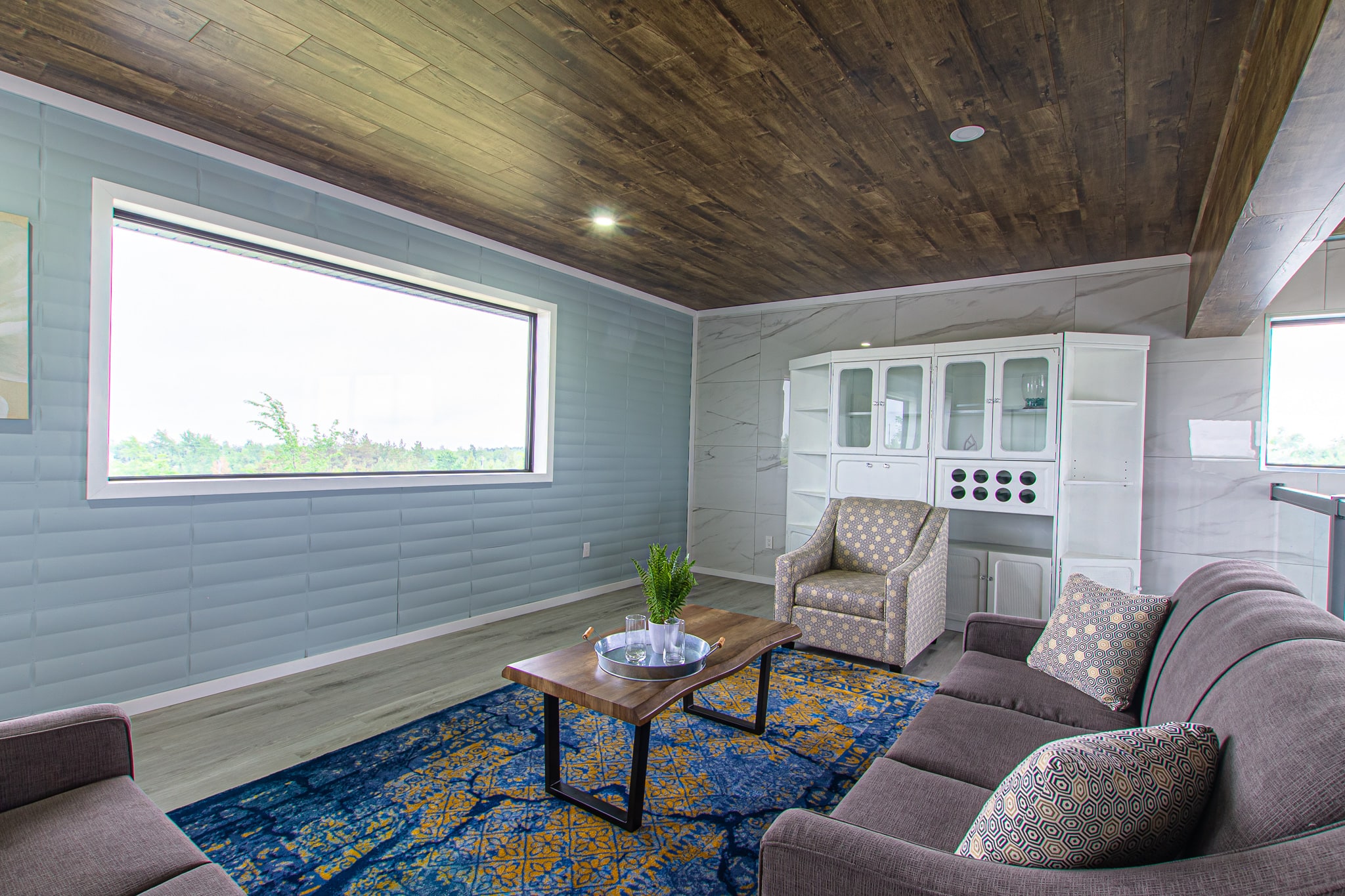A quiet upstairs sitting room with sofas, a glazed hutch and a long ribbon window